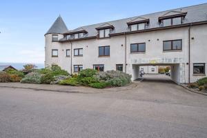a large white building with a parking lot at Boutique Beachside Apartment with Jacuzzi Bath, Findhorn in Findhorn