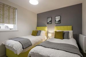 a bedroom with two beds and a window at Boutique Beachside Apartment with Jacuzzi Bath, Findhorn in Findhorn