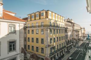 ein gelbes Gebäude in einer Stadt mit Straße in der Unterkunft Grand Ouro Deluxe Apartment Downtown Baixa in Lissabon