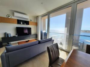 a living room with a blue couch and a large window at Cloud 7 Quality Sea Front Apartment in Marsaskala +4 photos