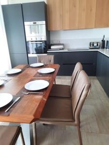 a kitchen with a wooden table with plates and chairs at Cloud 7 Quality Sea Front Apartment in Marsaskala