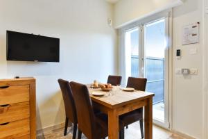 comedor con mesa, sillas y TV en Appartement Portofino - Welkeys, en Antibes