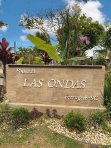 a sign in front of a park with trees at Pousada Las Ondas in Garopaba