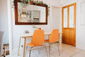 a dining room table with orange chairs and a mirror at 3 Bed - Modern Comfortable Stay - Preston City Centre in Preston