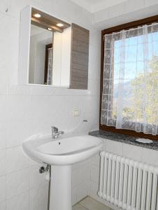 a white bathroom with a sink and a window at Stars Apartments Gressan in Cerise