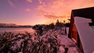 a view of a lake with snow covered trees and a building at Cabañas Aucaman in Villa Pehuenia