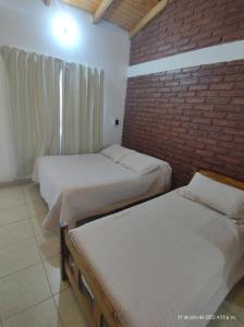 a bedroom with two beds and a brick wall at Hotel Juanita in Puelches