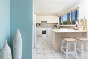 a kitchen with a counter and two stools in it at Coral Sands 2 in Forster