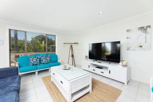 a living room with a blue couch and a tv at Coral Sands 2 in Forster
