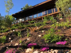 a house on top of a hill with flowers at Chalet DesignPur on the lake in Chertsey