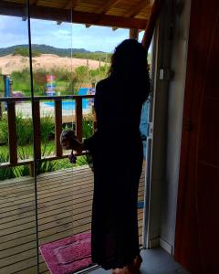 a woman standing on a balcony looking out the window at Caminho das Dunas - Studios próx Praia do Rosa e Ouvidor in Praia do Rosa