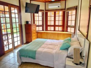 a bedroom with a bed and a tv and windows at Chalé das Águas in Igaratá