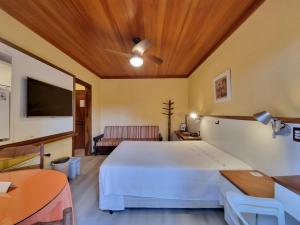 a bedroom with a large white bed and a flat screen tv at APARTAMENTO GRAMADO HOTEL in Gramado