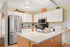 a kitchen with white cabinets and a stainless steel refrigerator at Walk to Downtown Festivities 2Bd2Ba Condo in Leavenworth