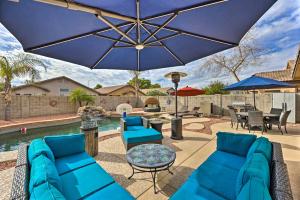 a patio with blue furniture and an umbrella at Radiant Peoria Paradise House with Pool and Patio! in Peoria