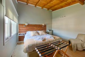 a bedroom with a bed and a chair and a window at CASA COIHUE in El Chalten