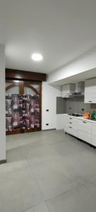 cocina grande con armarios blancos y suelo blanco en Denda House, en Mariglianella