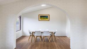 a white dining room with a table and chairs at Cabana Feliz Yamba, Pet Friendly Cottage in Yamba