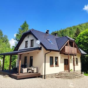une petite maison blanche avec un toit dans l'établissement Dom nad rzeką, à Nowy Gierałtów