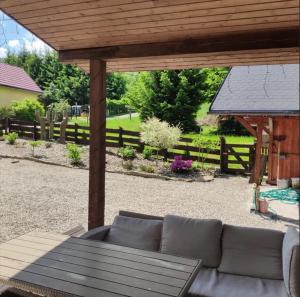 une terrasse avec un canapé sous une pergola en bois dans l'établissement Dom nad rzeką, à Nowy Gierałtów