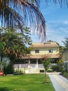 a yellow house with a palm tree in the yard at ReCanto dos Passáros - Guaratiba in Pedra de Guaratiba