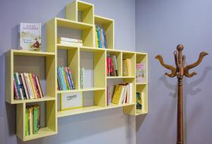 a yellow book shelf on a wall with books at 4 BR apartment & BBQ veranda in Tirana