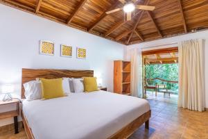a bedroom with a large white bed with yellow pillows at Makanas Beach Bungalows in Santa Teresa Beach