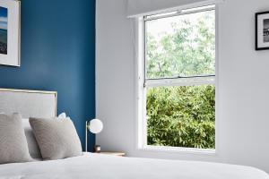 ein Schlafzimmer mit blauen Wänden und einem Fenster in der Unterkunft Stylish Townhouse in Melbourne's Playground in Melbourne
