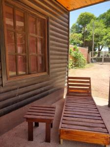 a porch with two wooden benches and a window at Cabañas Las Delicias in Salta