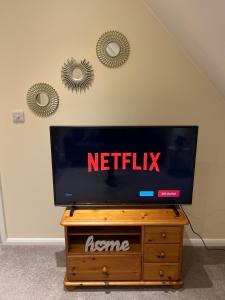 a flat screen tv sitting on top of a wooden dresser at Harrietsham House in Kent