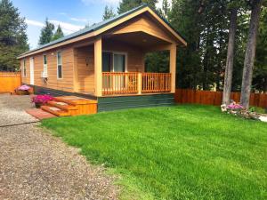 a log cabin with a porch and green grass at Alpine #1 in West Yellowstone