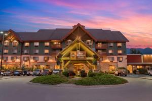 Best Western Plus Fernie Mountain Lodge في فيرني: فندق كبير فيه سيارات متوقفة في مواقف