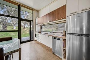 eine Küche mit einem Kühlschrank aus Edelstahl und einem Fenster in der Unterkunft Ecocrackenback 9 Sustainable chalet close to the slopes in Crackenback