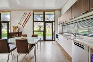 a kitchen with a table and chairs and windows at Ecocrackenback 9 Sustainable chalet close to the slopes in Crackenback