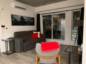 a living room with a couch and a chair with red pillows at Joli condo en basse-ville - Parking gratuit 309357 in Quebec City