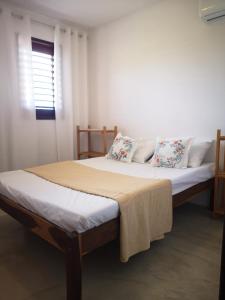 a bedroom with a large bed with pillows and a window at Morada Patacho in Pôrto de Pedras