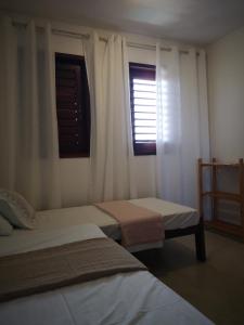 a bedroom with two beds and a window at Morada Patacho in Pôrto de Pedras