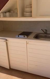 uma cozinha com armários brancos e um lavatório em Ocean dream em Sainte-Anne