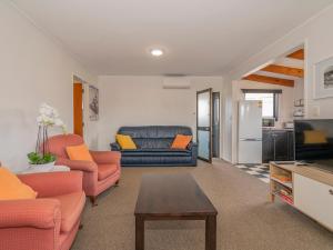 a living room with orange and blue furniture and a refrigerator at Surfscape - Whitianga Holiday Home in Whitianga