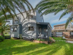a tiny house in a yard with a palm tree at Surfscape - Whitianga Holiday Home in Whitianga