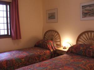Habitación con 2 camas y mesa con lámpara. en Tamara, en Acantilado de los Gigantes