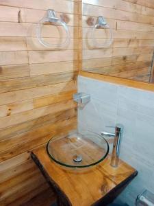 baño con lavabo de cristal en una pared de madera en Glamping Bellavista en La Vega