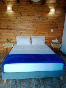 1 dormitorio con 1 cama grande y paredes de madera en Glamping Bellavista en La Vega