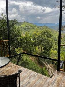 a balcony with a table and a view of a forest at Glamping Bellavista in La Vega