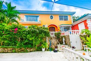 a yellow and orange house with a white fence at Palms Cottage at Viking Hill in Nassau