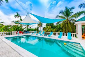 een zwembad met blauwe en witte stoelen en een tent bij Palms Cottage at Viking Hill in Nassau
