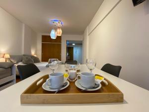 a table with a tray with two cups and glasses on it at Monoambiente de diseño confortable -Puerto Madryn in Puerto Madryn