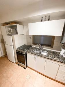 a small kitchen with a sink and a refrigerator at Monoambiente de diseño confortable -Puerto Madryn in Puerto Madryn