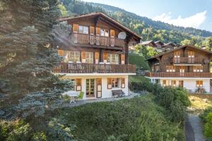 a large wooden house with a balcony on a hill at Wasserhügeli in Fiesch