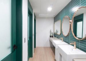 a bathroom with two sinks and two mirrors at Brosis Hotel in Busan